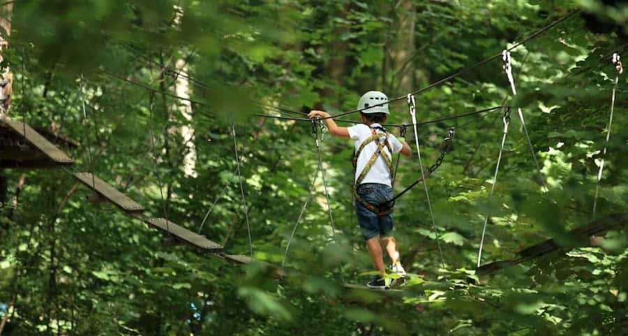 Enfant sur un parcours d'accrobranche à Saint-Molf - Camping Paradis l'Île de Kernodet